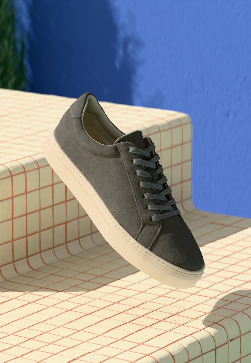 Hall hall sneakers, ümmarguse varbaga, lamedate beežide tallade ja sama tooni paeltega, millel on mustriline pind sinise tausta ees.
