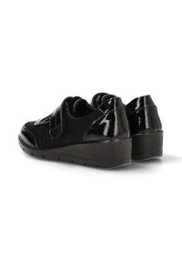 Scarpe in pelle verniciata nera con punta arrotondata, cinturino in Velcro e tacco basso a cuneo. Presentano dettagli perforati sui lati.