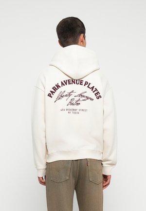 Cream-colored hoodie with a large burgundy graphic on the back reading "PARK AVENUE PLATES" and additional text. Cotton material, relaxed fit.