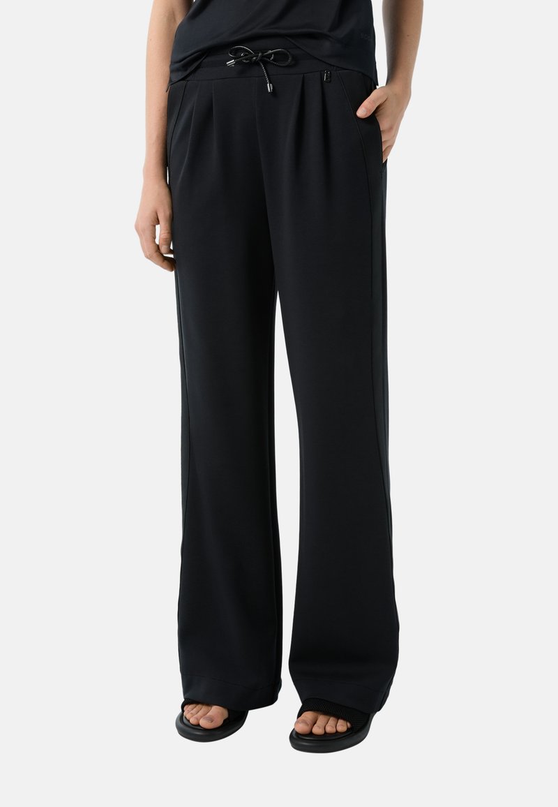 Zwarte wijde broek van zacht materiaal, met een trekkoord in de taille, zijzakken en een gladde textuur.