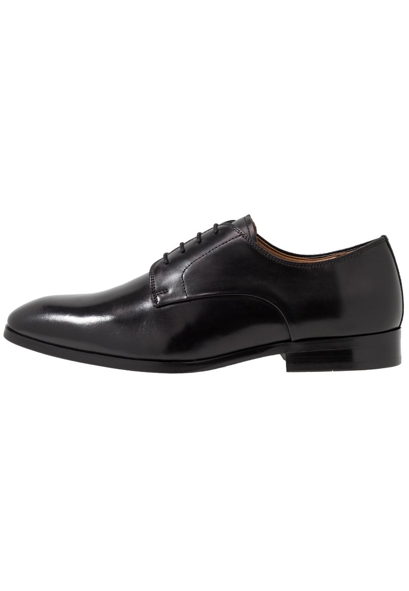 Chaussure oxford formelle en cuir noir avec un laçage fermé, un bout pointu et un petit talon empilé, présentée en profil droit sur fond blanc.