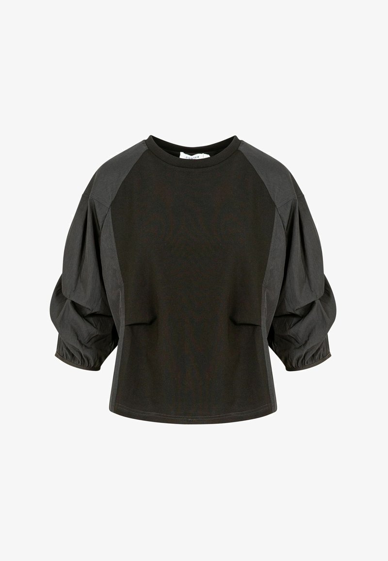 Haut noir à coupe ample avec manches trois-quarts bouffantes et encolure ronde, présentant des panneaux de tissu contrastants sur les épaules et les manches.