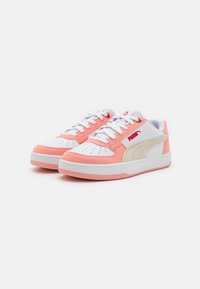 Puma sneakers featuring a white upper, peach accents, and beige side panel, with a textured sole and contrasting pink outsole.