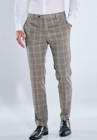 Beige karierte Hose mit maßgeschneiderter Passform, flacher Vorderseite, Seitentaschen und passenden Gürtelschlaufen, kombiniert mit schwarzen Anzugschuhen.