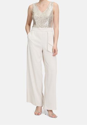 Bezrekawowy top z cekinami w kolorze złotym, zestawiony z białymi spodniami o szerokich nogawkach, posiadającymi boczne kieszenie i przedni zagięcie. Srebrne sandały na obcasie.