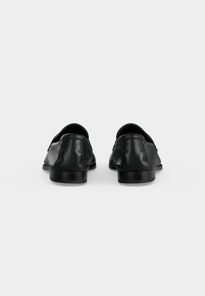 Paire de chaussures habillées en cuir noir vues de dos sur un fond blanc uni.