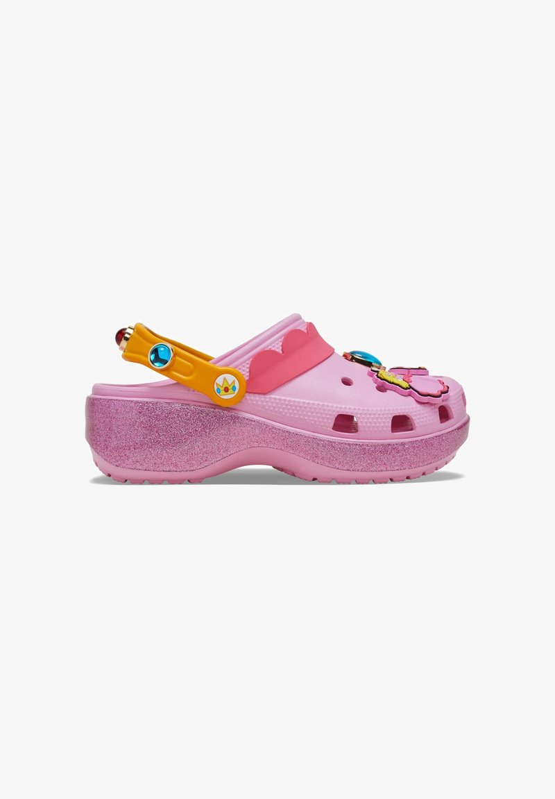 Pink platform clog with glitter sole, orange adjustable strap with blue gem, and colorful decorative charms on top.