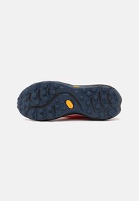 Suela de zapato de goma con tacos redondeados y profundos para tracción, con una base predominantemente azul y un logo de Vibram amarillo cerca del centro.