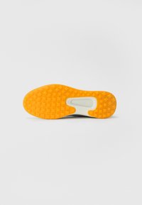 Semelle de chaussure avec un fond en caoutchouc orange texturé, présentant un motif en losange et une semelle intermédiaire blanche à la finition lisse et avec un détail de marque.