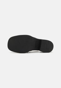 Talpa de pantof din piele neagră cu o suprafață netedă și plată, vârf rotunjit, toc ușor și cusături subtile pe margine.