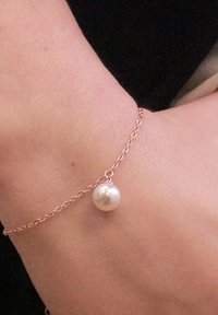 Bracciale in oro rosa con una singola perla bianca; design delicato con texture liscia e forma semplice e rotonda.