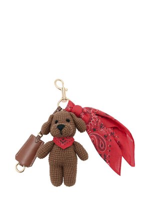 Portachiavi a forma di cane marrone all'uncinetto con bandana rossa intorno al collo, attaccato a una clip dorata con accessorio in tessuto rosso decorato e piccola pochette marrone.