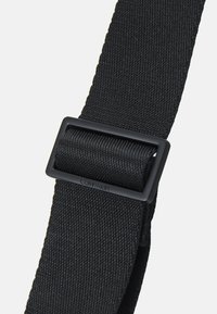 Black cotton strap with a textured surface, featuring a matte black rectangular buckle and embossed branding detail.