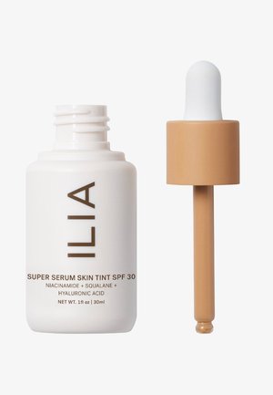 ILIA Super Serum Skin Tint SPF 30 dans un flacon en verre blanc, avec un capuchon compte-gouttes. Texte sur le flacon en brun. Contient de la niacinamide et du squalane.