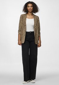 Blazer s leopardím vzorem vyrobený z měkké látky, dlouhé rukávy, otevřený přední design, spárovaný s černými kalhotami s vysokým pasem a širokými nohavicemi a teniskami.