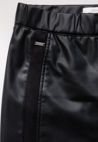 Zwarte neplederen rok met een gladde textuur, een elastische tailleband, een contrasterende suède paneel en een kleine metalen accenten.