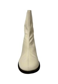 Bota de cuero color crema hasta la rodilla con punta afilada, textura suave, costuras visibles en la costura trasera y suela plana negra.