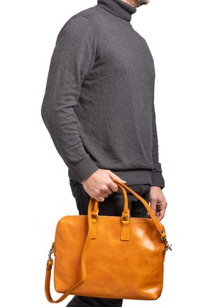 Sac à main en cuir tan avec deux poignées supérieures et une bandoulière réglable. Texture lisse et forme rectangulaire avec une fermeture éclair.