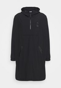 Schwarze lange Windjacke mit Kapuze, Viertel-Reißverschluss, verstellbaren Bündchen, einer frontalen Tasche und seitlichen Reißverschlusstaschen. Glattes, leichtes Material.