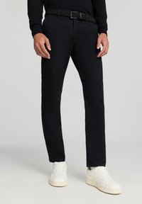 Czarne bawełniane spodnie o slim fit, z tkaną paskiem o fakturze. W połączeniu z białymi trampkami, wygląd jest swobodny i nowoczesny.