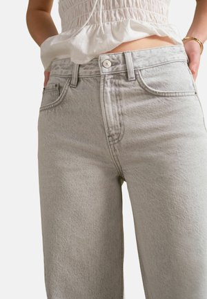 Jean taille haute gris clair en denim, avec une coupe droite, des poches avant et une fermeture à bouton.