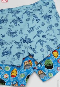Modré boxerky s grafikou superhrdinů Marvel; jedny mají modré ilustrace na světle modrém pozadí, druhé mají barevné obličeje postav na modrém.