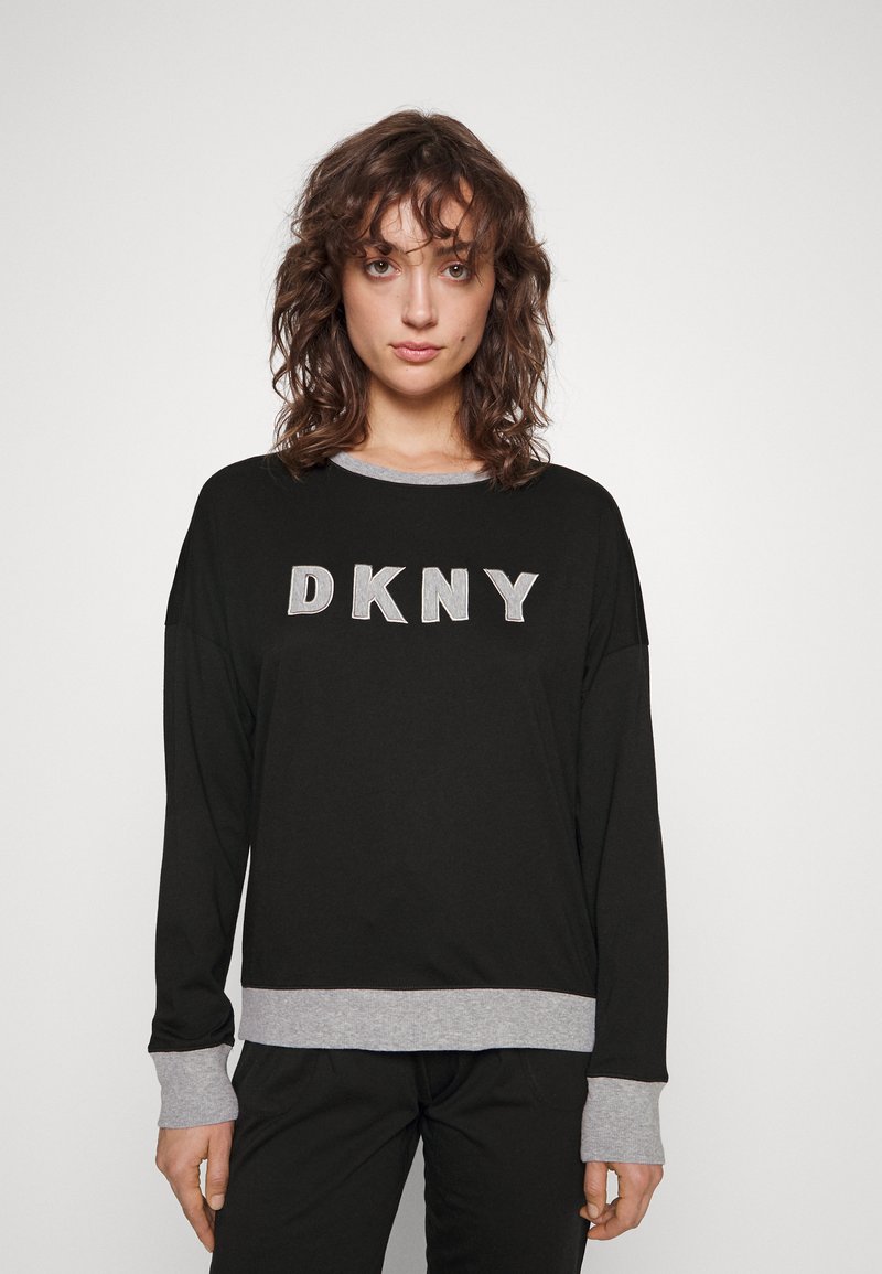 Sudadera negra de manga larga con cuello y puños grises, que presenta "DKNY" en letras plateadas en el pecho. Tela suave y casual.