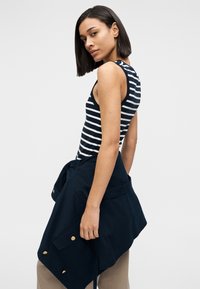 Ριγέ κοντομάνικο μπλουζάκι σε ναυτικό μπλε και λευκό με εφαρμοστή γραμμή. Συνδυασμένο με ναυτικό μπλε σακάκι δεμένο στη μέση. Ομαλό ύφασμα με κομψές γραμμές.