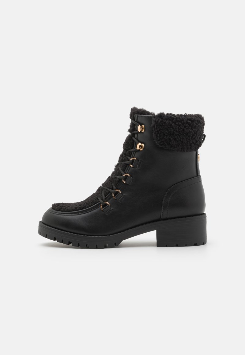 Bottines noires avec un col en fausse fourrure, dotées d'une finition en cuir lisse, d'œillets en métal et d'un talon bloc avec une semelle texturée.