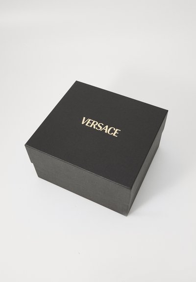 Cutie din carton negru cu o textura netedă, având un logo auriu "VERSACE" centrat pe capac. Marginile drepte, design simplu.