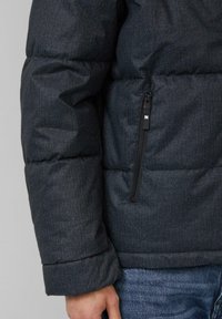 Kurtka puchowa w ciemnoszarym kolorze, z boczną kieszenią na zamek, pikowanym wzorem i mankietami. Casualowy design z detalami przeszyć.