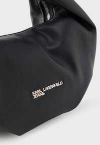 Μαύρη δερμάτινη τσάντα με υφή, με ασημί φερμουάρ και μεταλλικό λογότυπο "KARL LAGERFELD JEANS" στο μπροστινό μέρος.