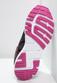 Suola di scarpa atletica nera con una intersuola bianca testurizzata e dettagli rosa. Profondi solchi e motivi per una maggiore trazione.