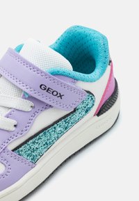 Violet ir balti sportbačiai su turkio spalvos tinkleliu ir blizgiu turkio spalvos šonu. Priedas - Velcro dirželis ir tekstūruotas juodas padas.