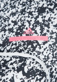 Svart och vit mönstrad atletisk tyg med en slät textur, som har en rosa "Stella McCartney"-etikett och en liten Adidas-logotyp.