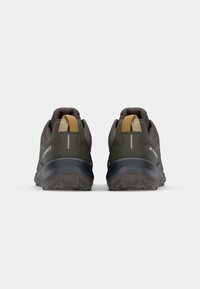 Groene buitenschoenen met een gestructureerde afwerking, voorzien van een verstevigde hak, oranje accenten en een robuuste rubberen zool voor grip.
