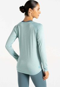 Hellblaues Langarm-Sportoberteil mit Rundhalsausschnitt und Raglanärmeln. Glatte Textur, minimalistische Markenkennzeichnung und lässige Passform.