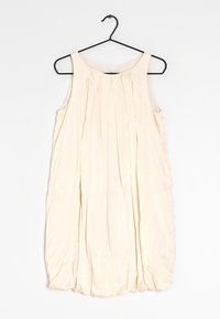 Pale beige sleeveless dress with subtle pleats, rounded neckline, and a flowing silhouette, made from a lightweight, textured fabric.