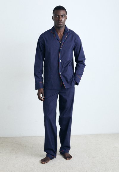 Ensemble de pyjama marine en coton avec des finitions en arc-en-ciel contrastées, comprenant une chemise à boutons avec une poche et un pantalon ample.