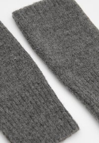 Szürke gyapjú lábmelegítők, texturált kötött mintával. Minden darab puha, bolyhos felülettel és bordázott tetejű szélekkel rendelkezik a még nagyobb kényelem érdekében.