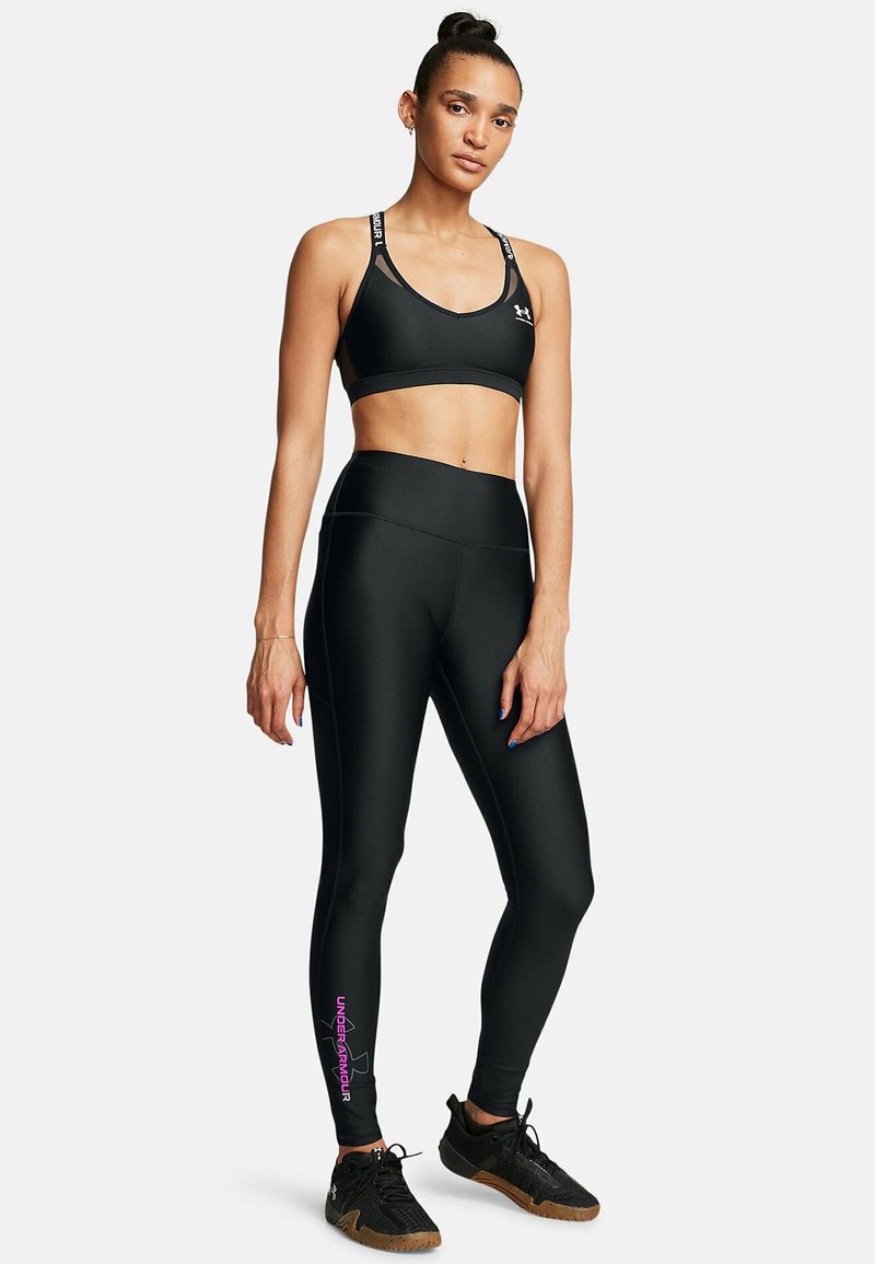 Sujetador deportivo negro y mallas con un diseño ajustado y una textura suave. El sujetador presenta un logo en las correas; las mallas tienen un logo rosa en el tobillo.