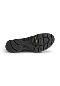 Semelle de chaussure de sport noire avec une bande de roulement en caoutchouc texturé, design flexible, et marquage en relief. Détails remarquables incluent un logo jaune et des motifs.