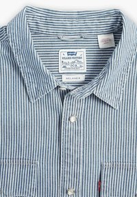 Niebiesko-biała, luźno dopasowana koszula w stylu western z napami, kieszenią na piersi i metką marki. Bawełniana tkanina o fakturowanym wykończeniu.