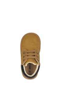 Bruine suède schoen met zwarte accents, ronde neus, twee-tonen veters en een gewatteerde binnenzool. Voorzien van een gestructureerde rubberen zool voor grip.