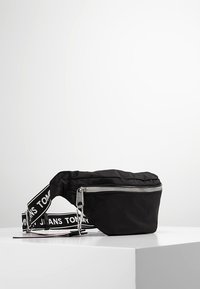 Svart nylon midjeväska med en silverfärgad dragkedja, utrustad med en justerbar axelrem med varumärke. Kompakt, rektangulär form med en slät yta.