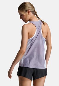 Canottiera sportiva viola chiaro con schiena in rete, design racerback e fori per la ventilazione, abbinata a pantaloni corti neri.