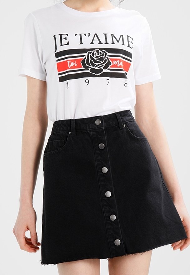 Camiseta blanca con texto negro "JE T'AIME" y un gráfico de rosa, combinada con una falda de mezclilla negra con botones frontales y dobladillo deshilachado.