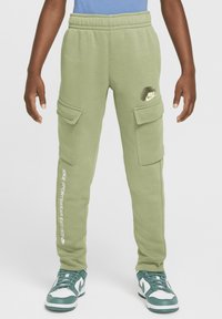 Pantaloni sportivi verde chiaro con tasche cargo, vita elastica e marchio Nike bianco sul lato. Abbinati a sneaker verdi e bianche.
