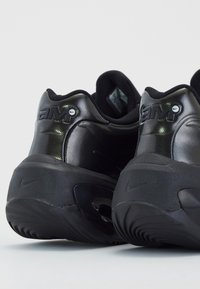 Paire de baskets Nike Air Max noires vues de dos, mettant en avant la semelle épaisse et le logo embossé au talon.