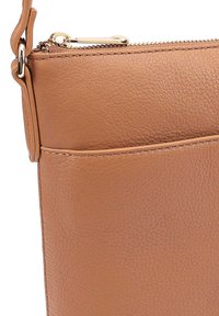 Bruine leren handtas met een getextureerd oppervlak, voorzien van een ritsafsluiting en een voorvak. Het stiksel aan de randen voegt detail toe aan het ontwerp.